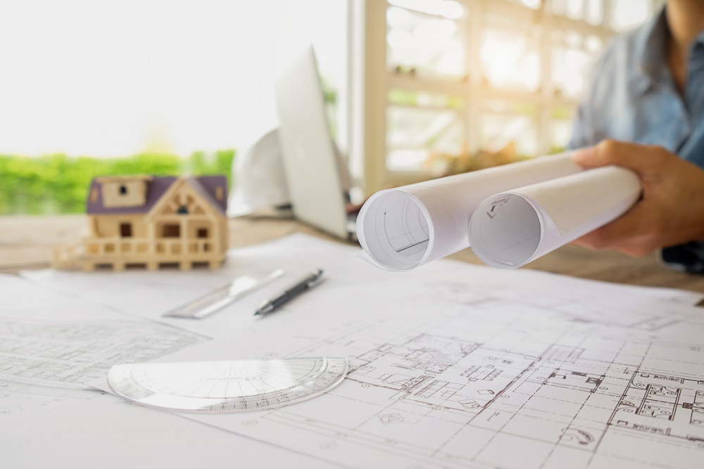 Équipe MGC travaillant sur des plans de construction, reflétant leur engagement envers un service personnalisé et des solutions innovantes pour clients particuliers et professionnels